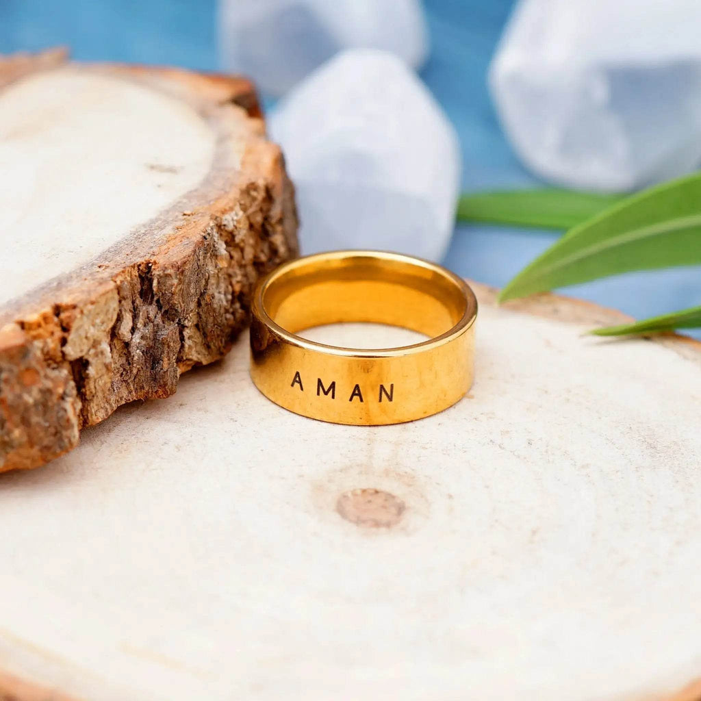Gold ring engraved with name Aman on wooden surface unique custom name jewelry by Gosarte Emporium